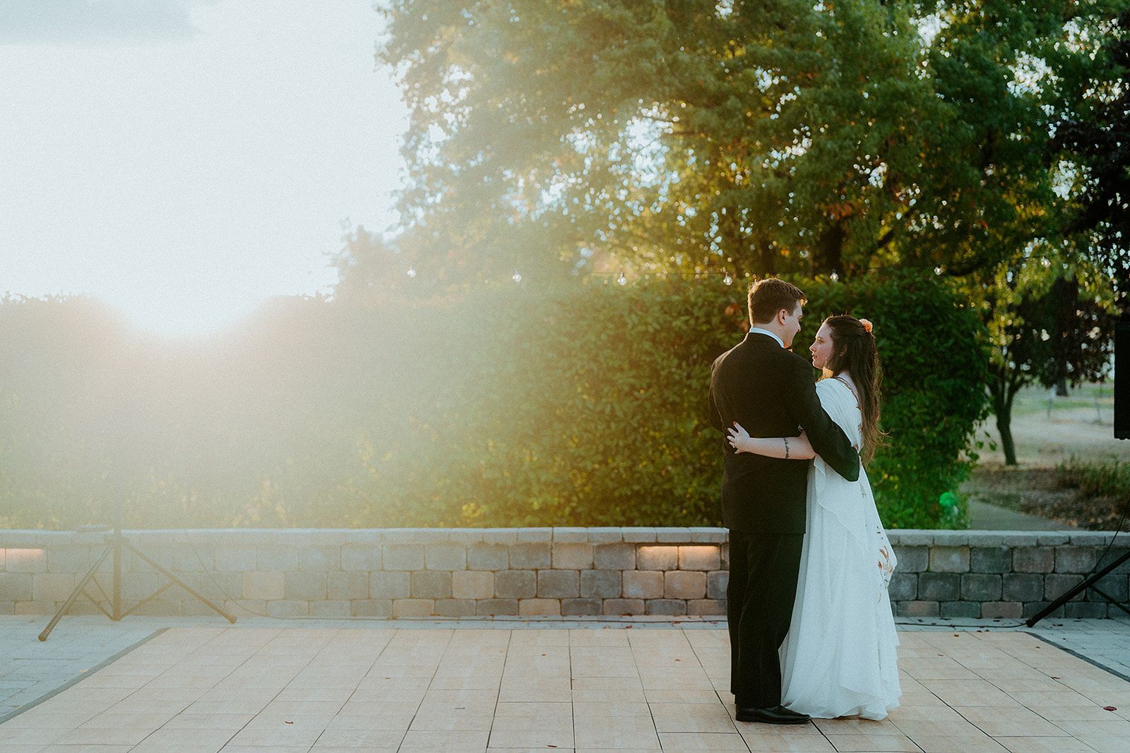 A bride and groom are standing next to each other on a patio.