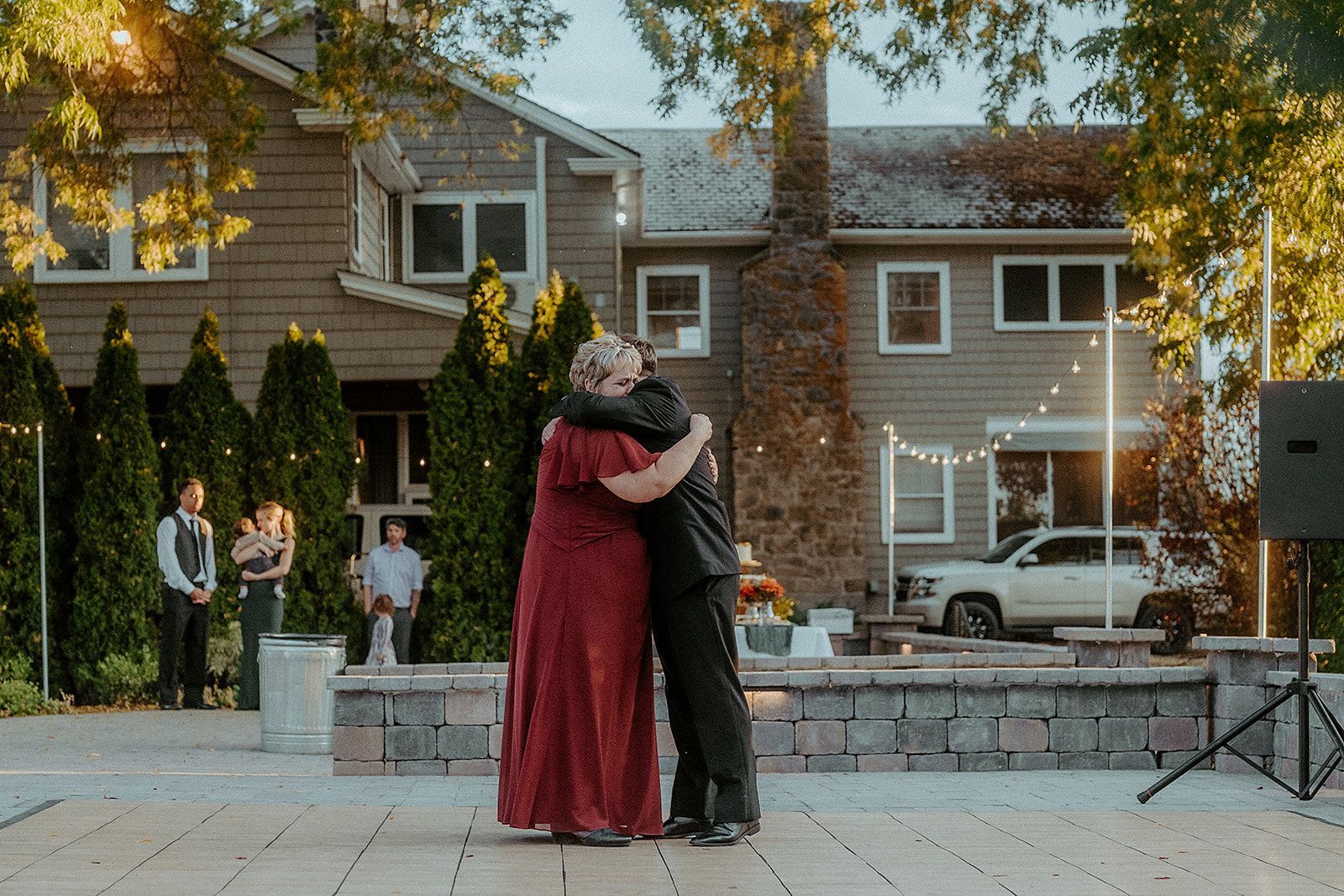A man and woman are hugging each other while dancing in front of a house.