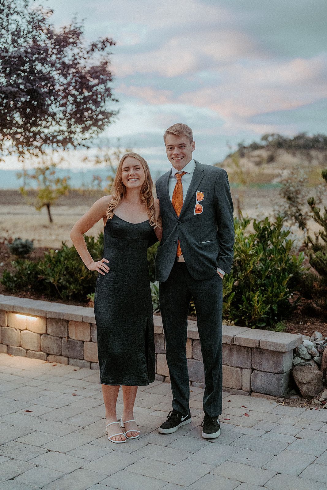 A man in a suit and tie is standing next to a woman in a dress.
