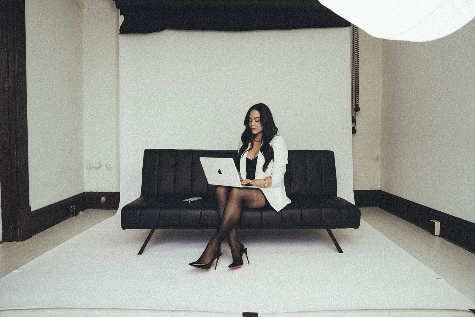 A woman is sitting on a couch using a laptop computer.