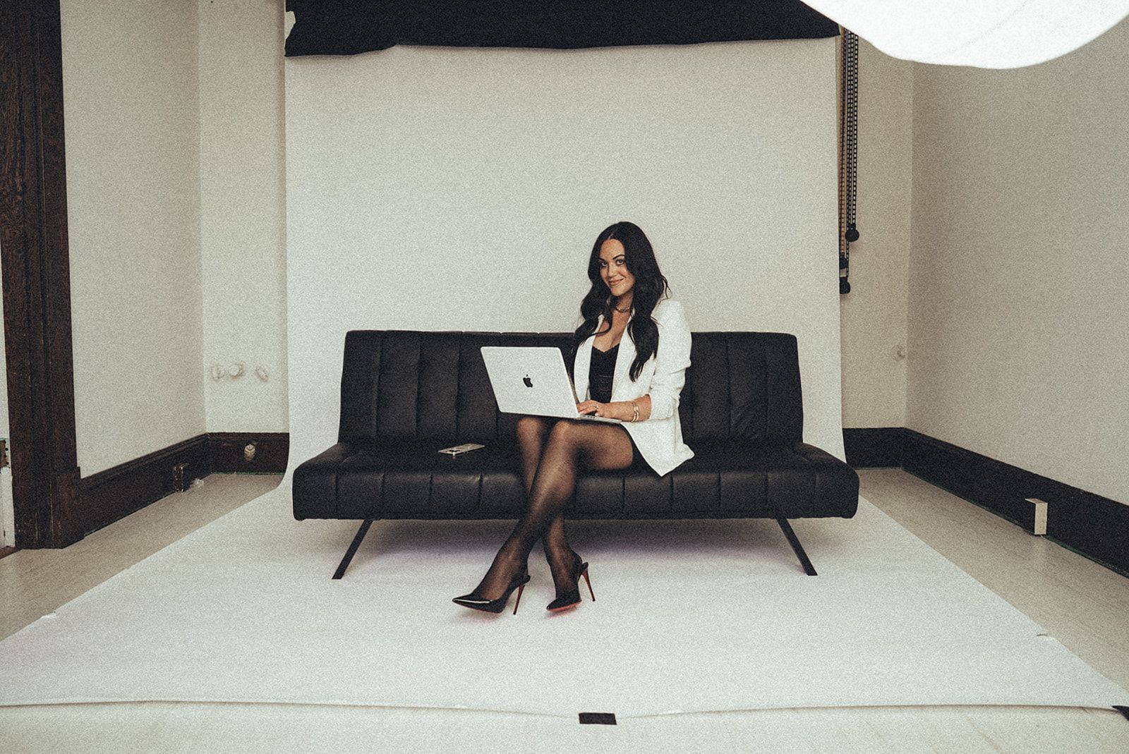 A woman is sitting on a couch with a laptop on her lap.