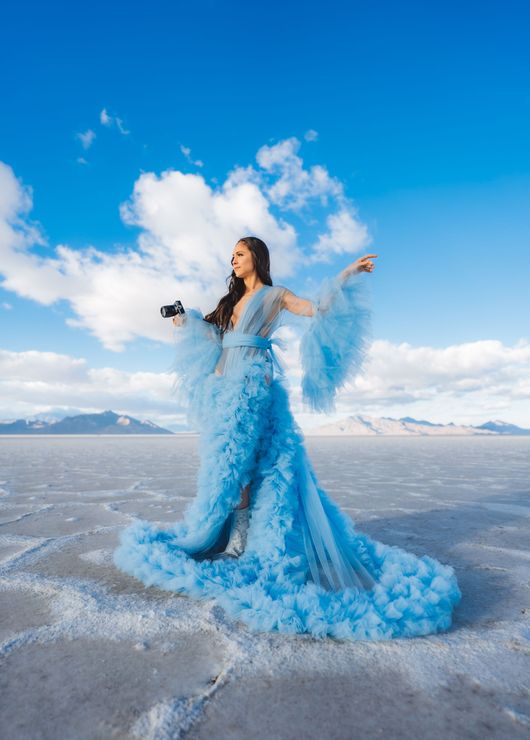 A woman in a blue dress is standing in the middle of a snowy field.