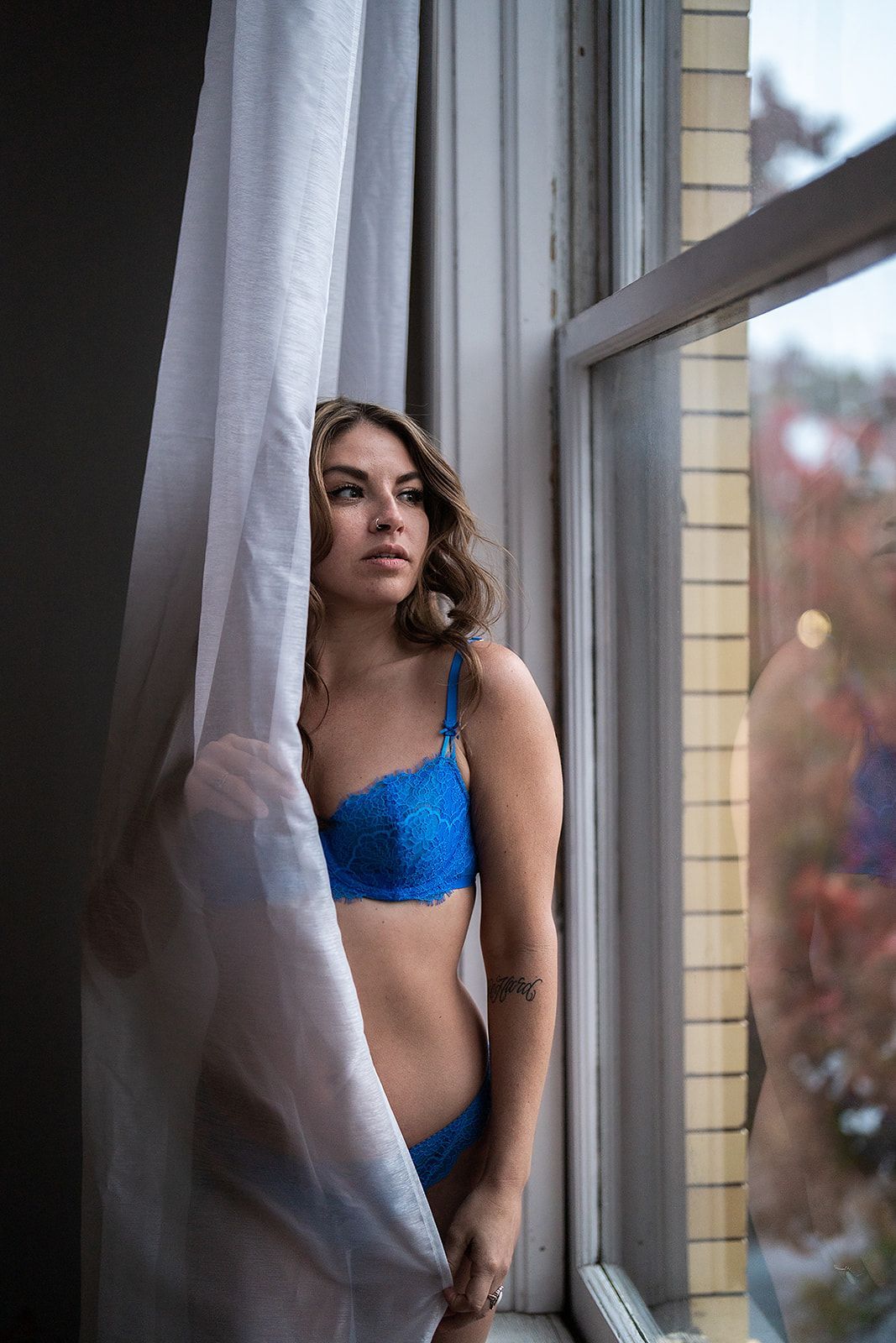 A woman in lingerie is looking out of a window.