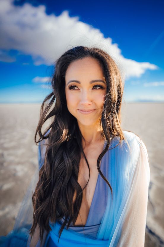 A woman in a blue dress is standing on a beach.