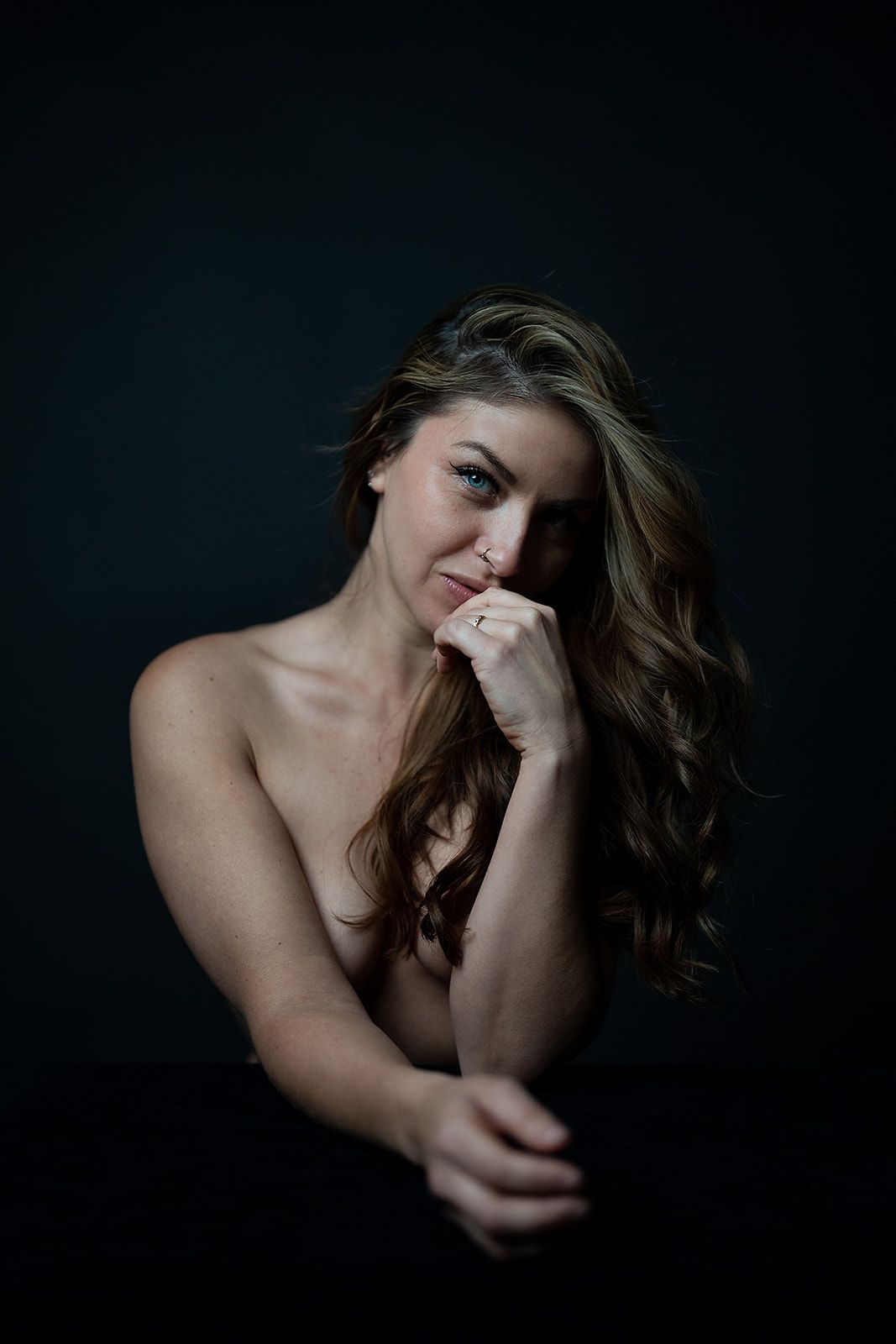 A woman is touching her face with her hands in the dark.