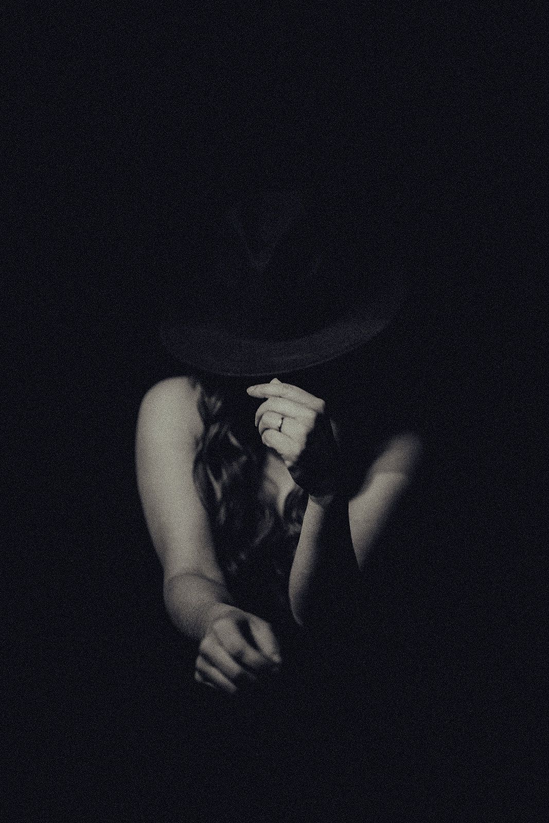 A woman is covering her face with her hands in the dark.