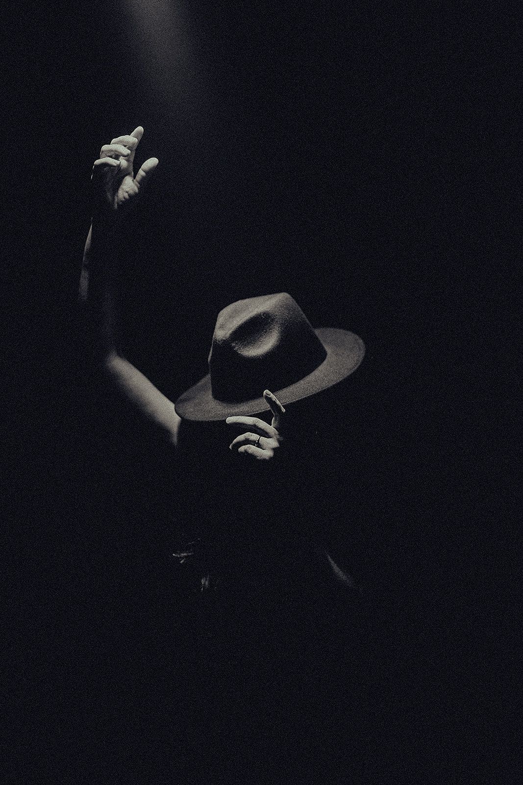 A black and white photo of a person wearing a hat in the dark.