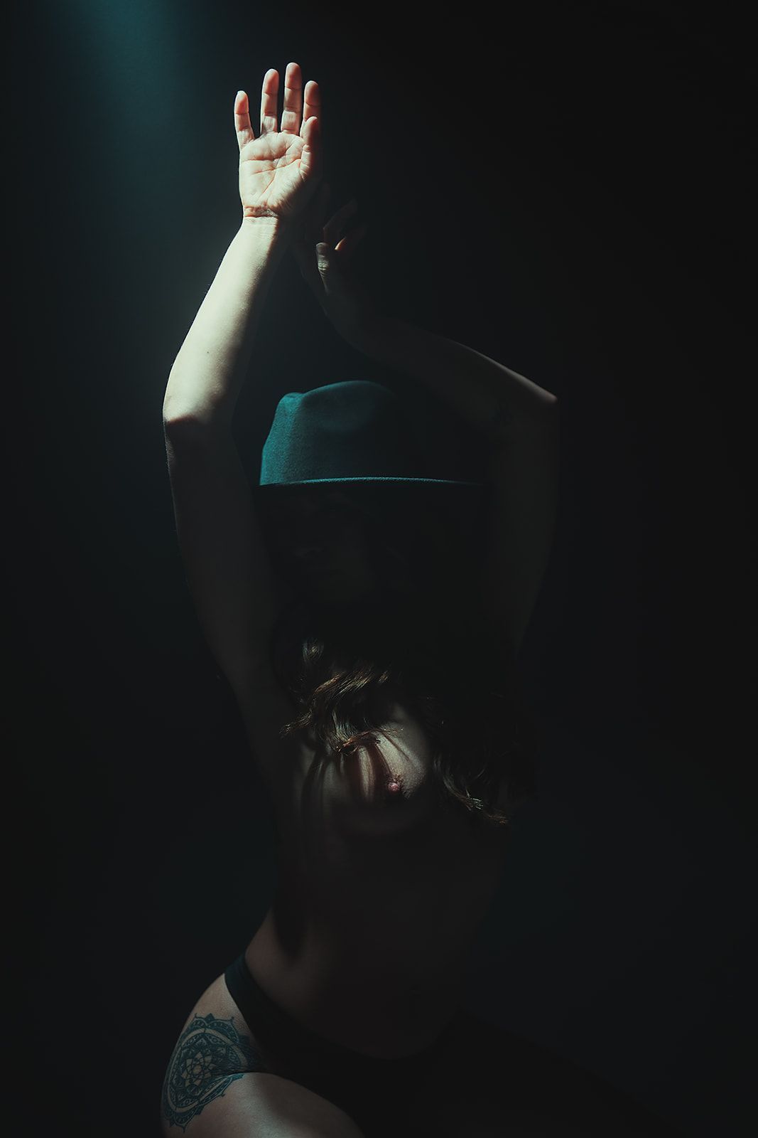 A woman is covering her face with her hands in the dark.