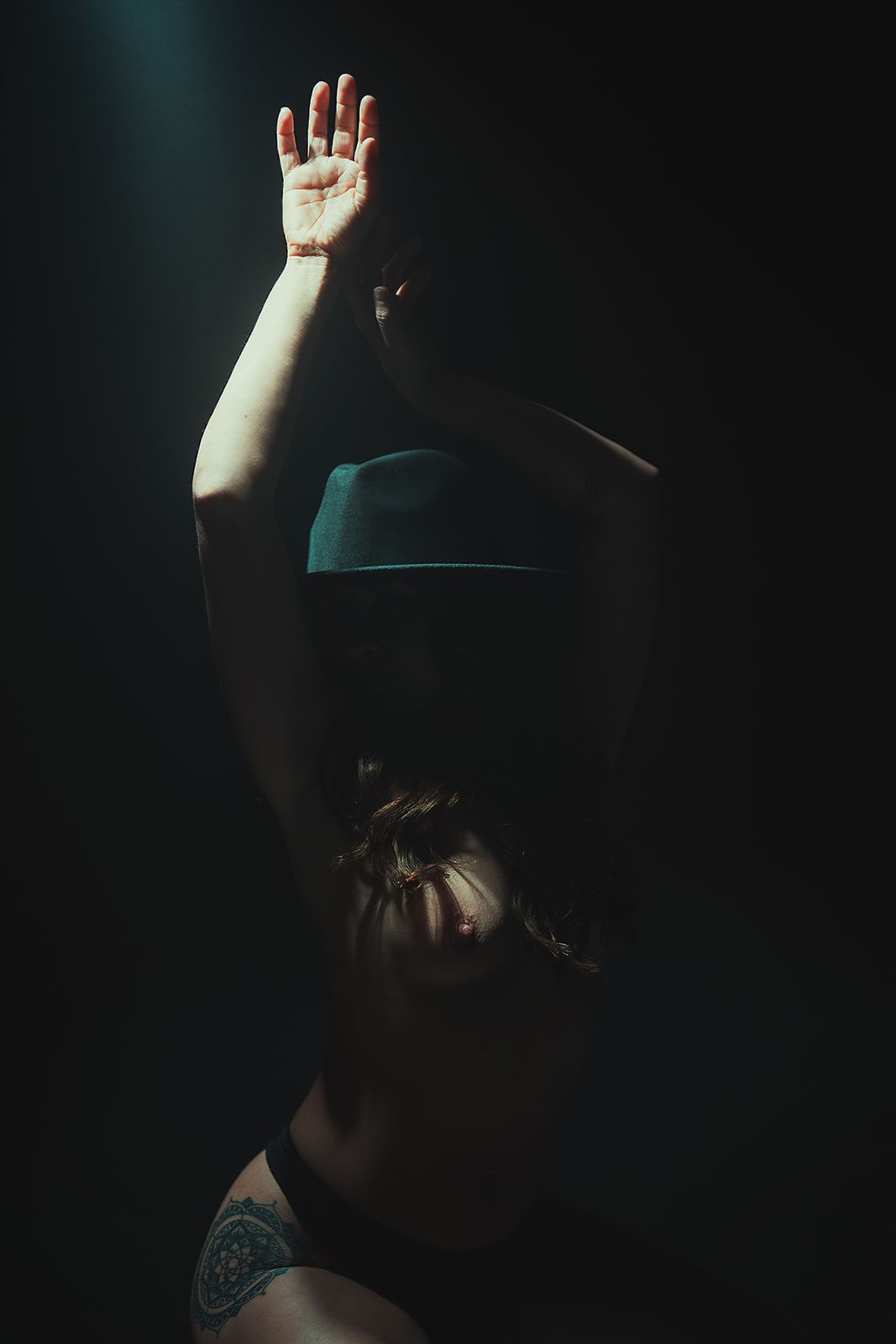 A woman is covering her face with her hands in the dark.