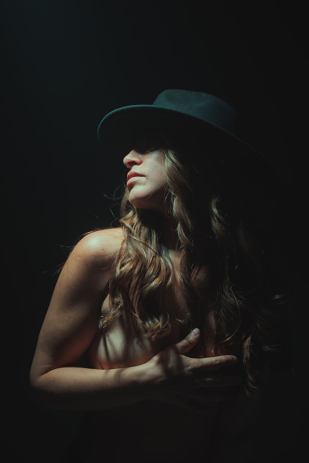 A woman is holding her chest with her hands in the dark.