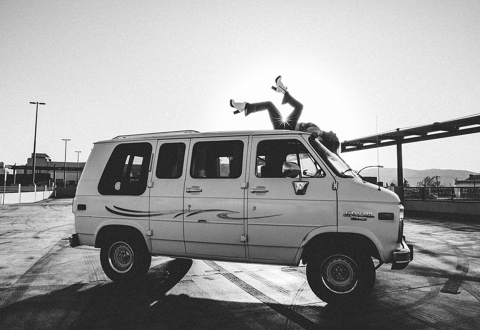 A black and white photo of a van with a person on top of it
