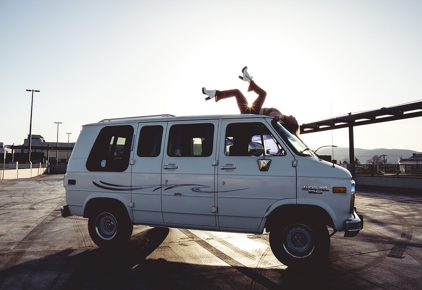 A person is laying on top of a white van