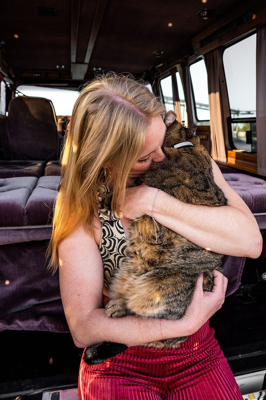 A woman is holding a cat in her arms in a van.