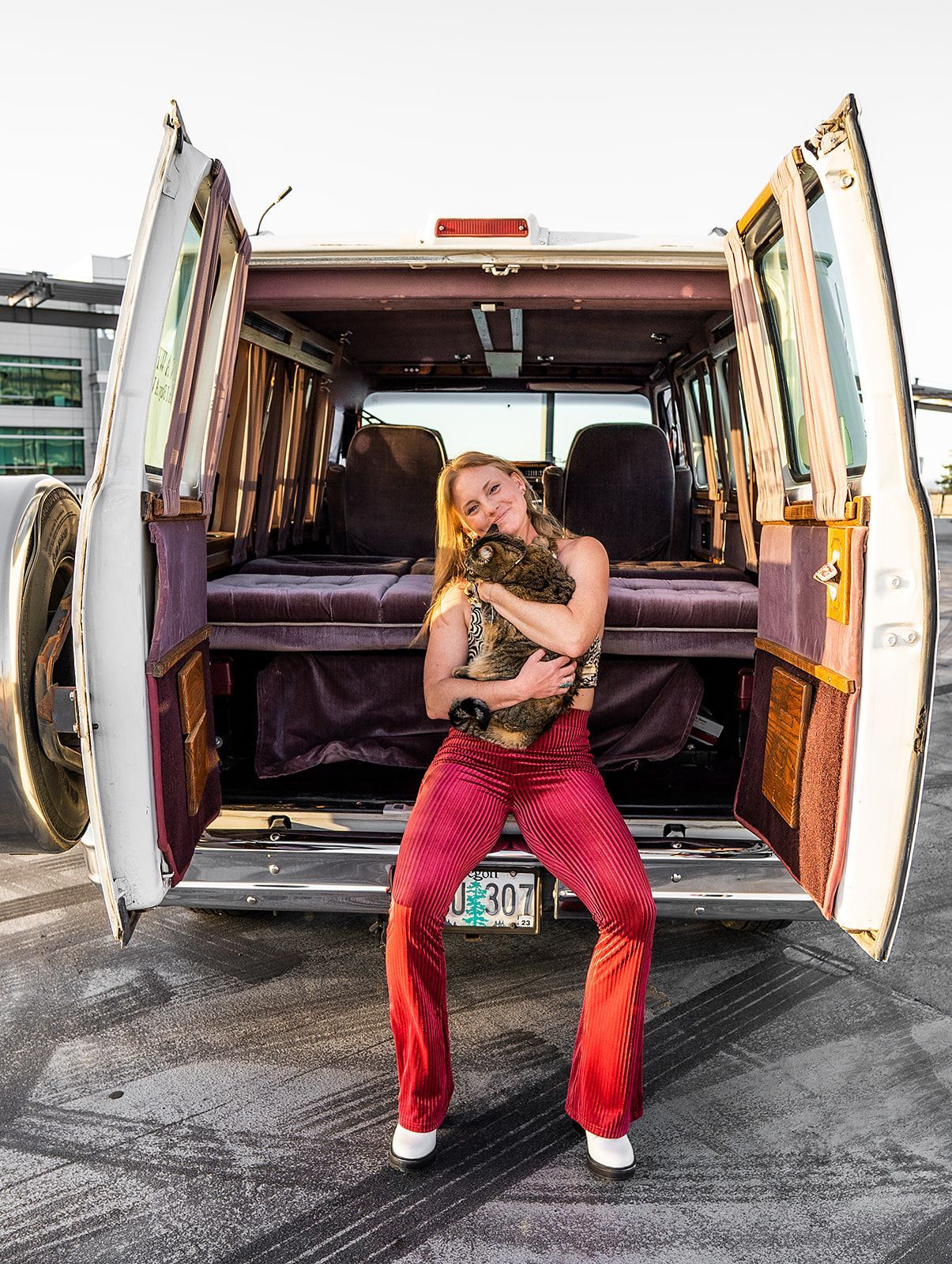 A woman is standing in the back of a van holding a cat.