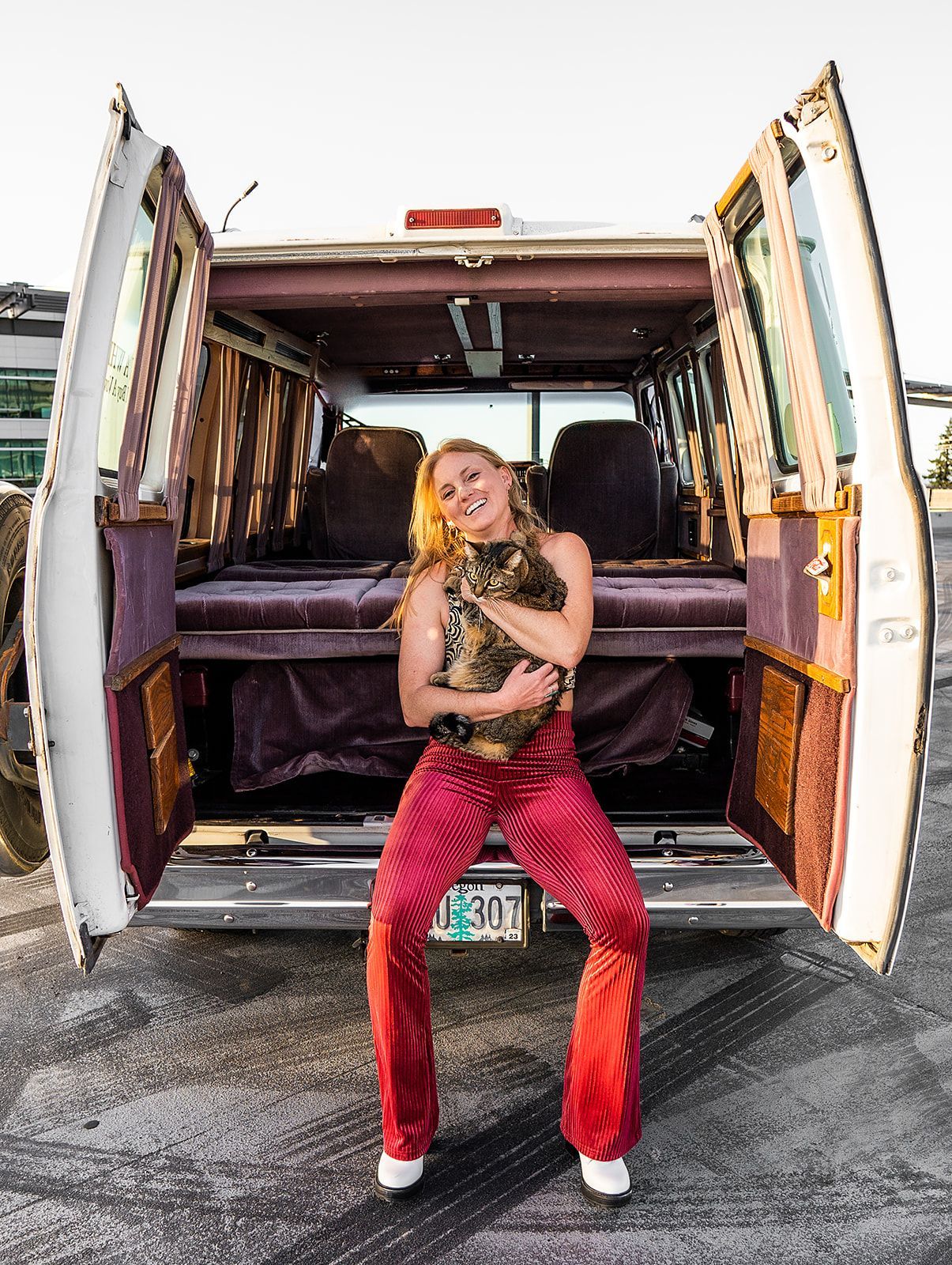 A woman is standing in the back of a van holding a cat.