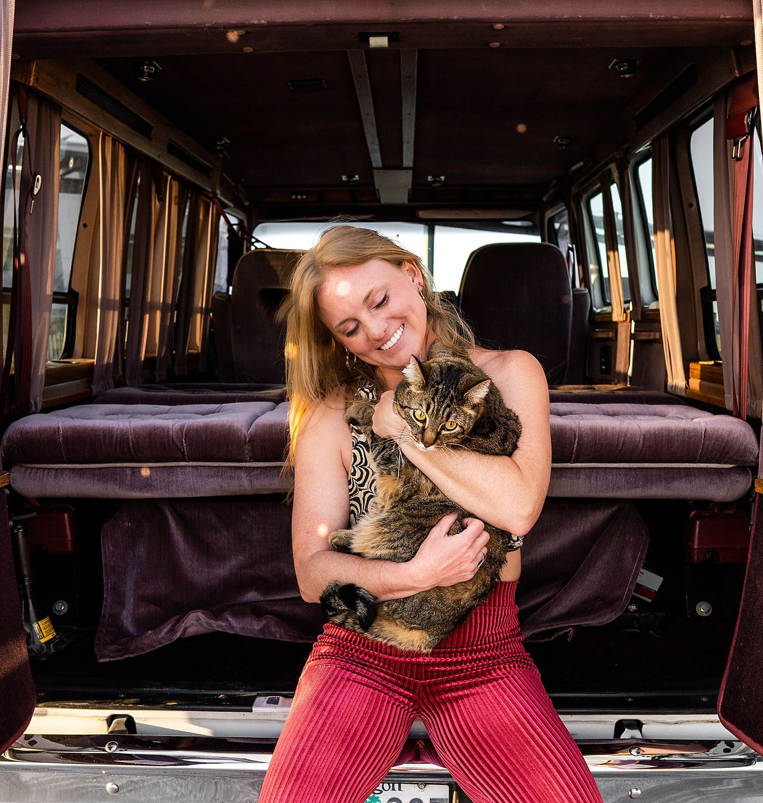 A woman is holding a cat in the back of a van
