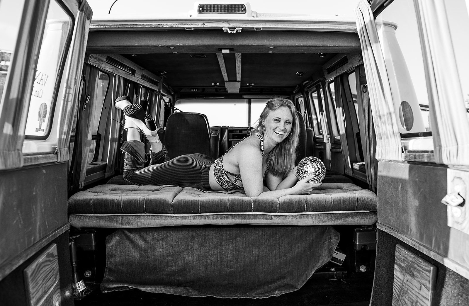 A woman is laying on a bed in the back of a van.