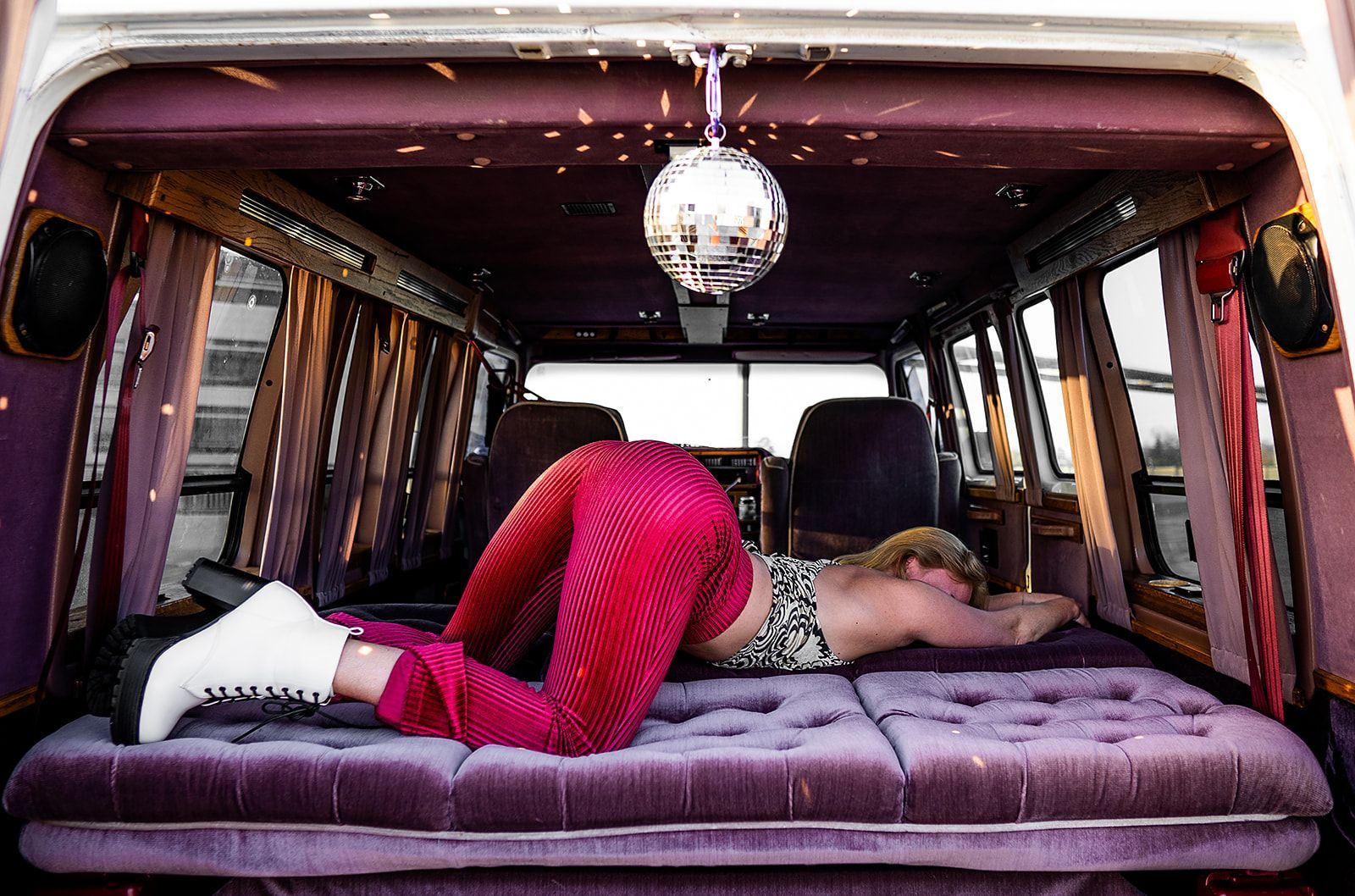 A woman is laying on a bed in the back of a van.