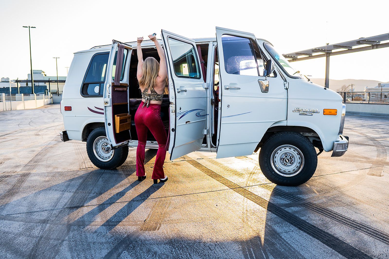 A woman is getting out of a white van in a parking lot.