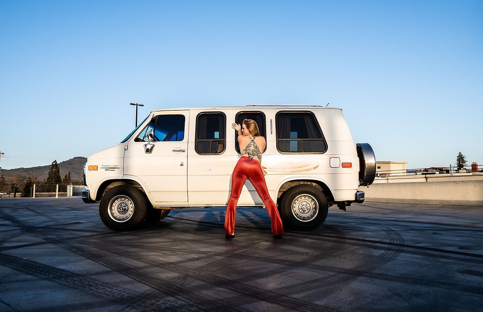 A woman is standing next to a white van in a parking lot.