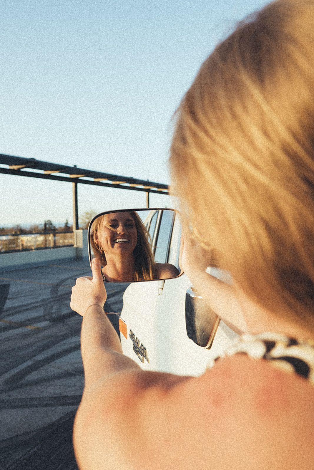 A woman is looking at her reflection in a mirror and giving a thumbs up.