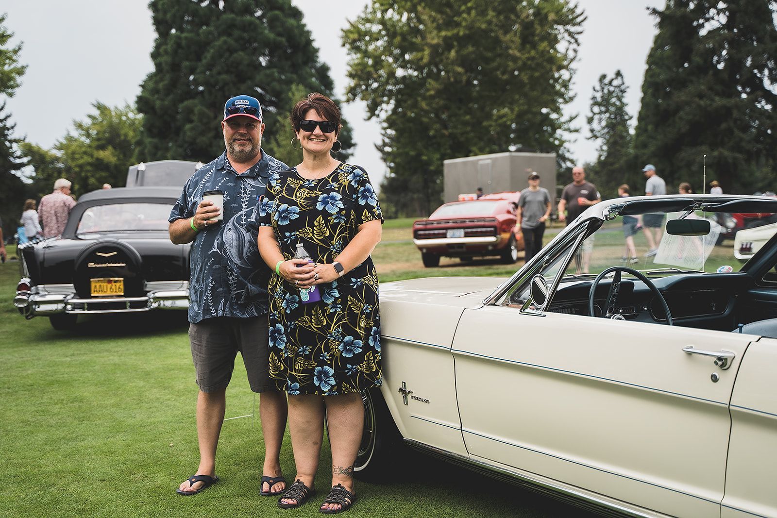 A man and a woman are standing next to a white car.