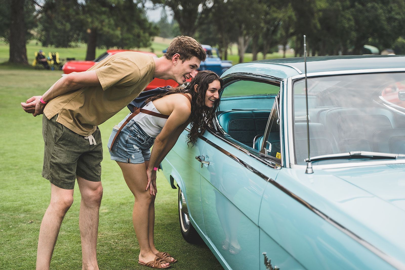 A man and a woman are standing next to a blue car.