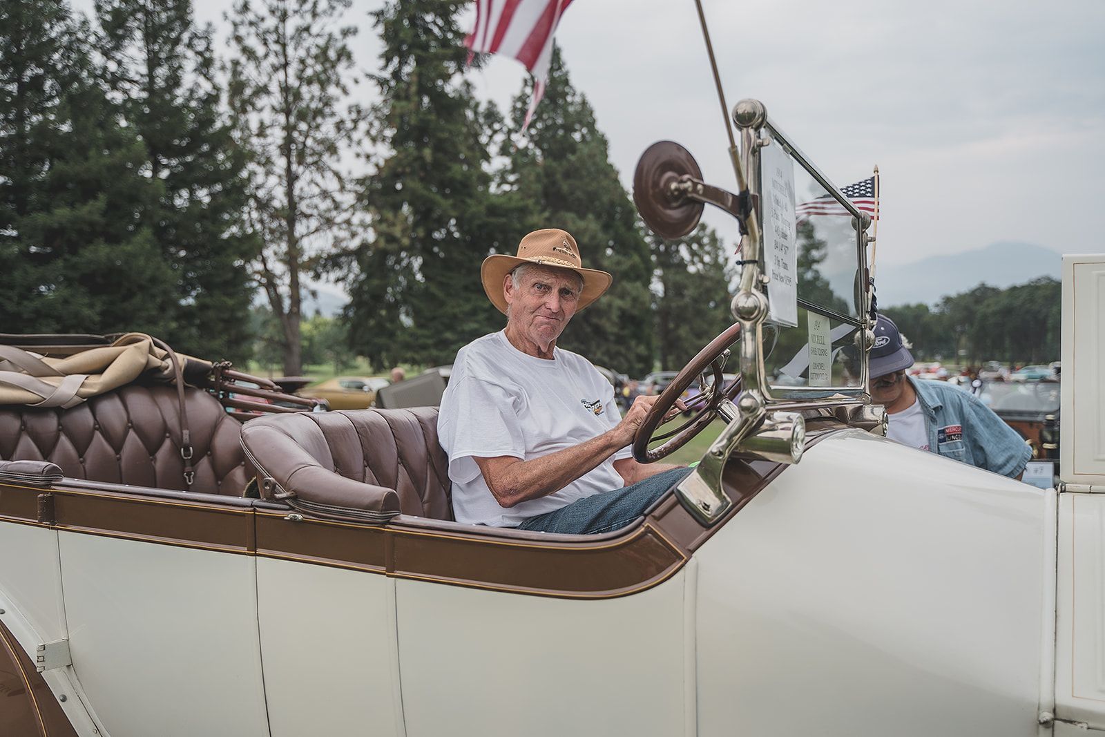 A man in a cowboy hat is driving an old car.