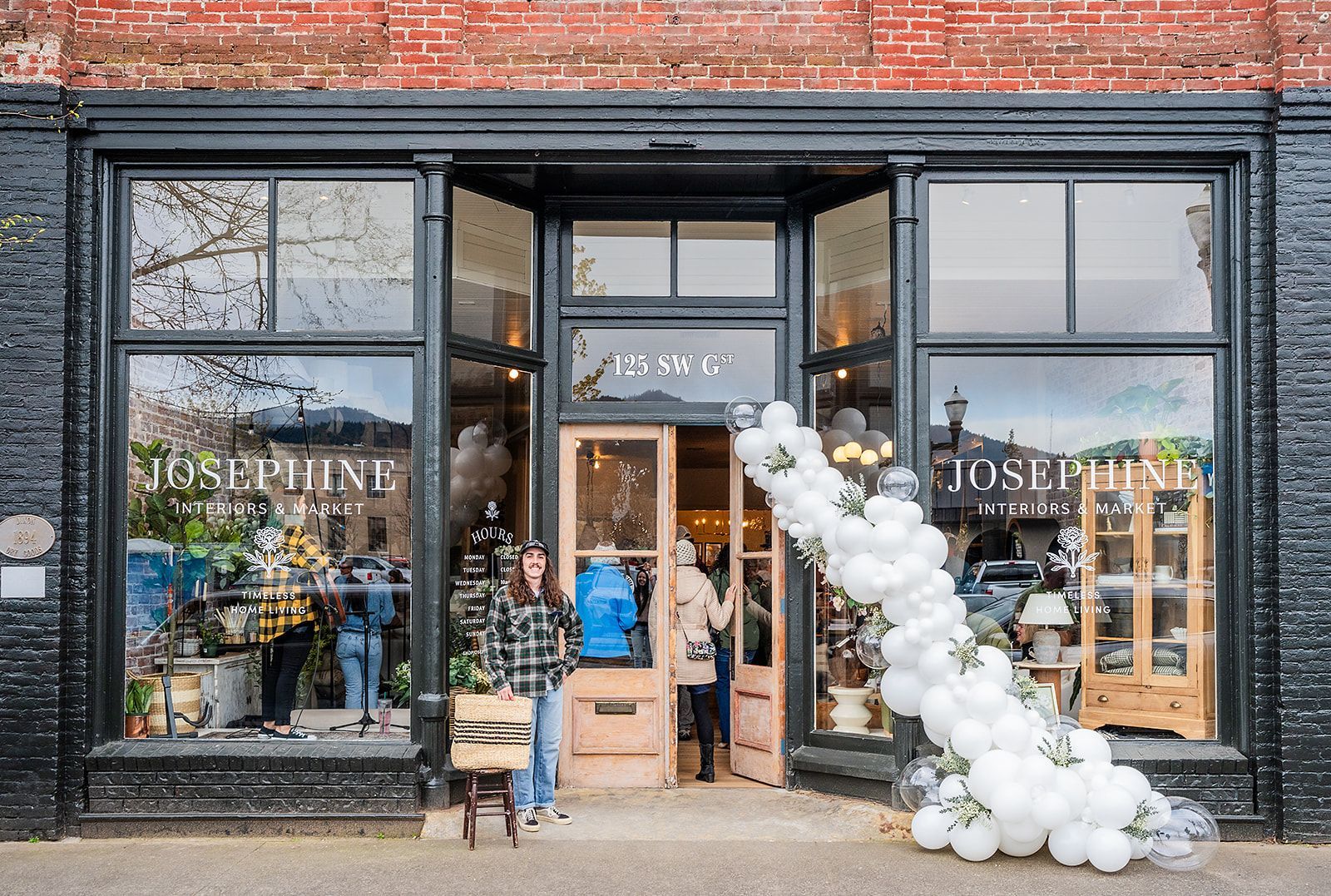 A woman is standing in front of a store with balloons in front of it.