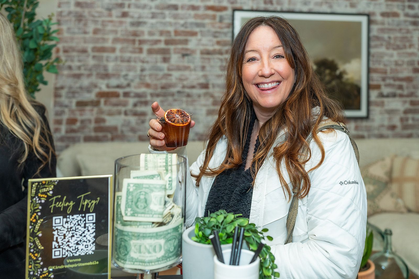 A woman is holding a cupcake in front of a jar of money.