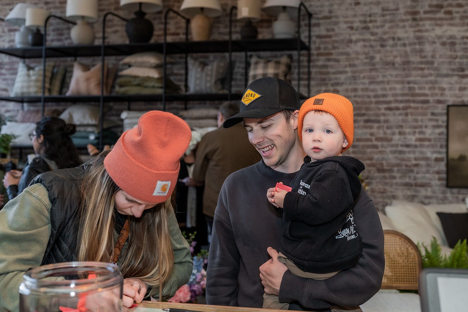 A man is holding a baby in his arms while a woman looks on.