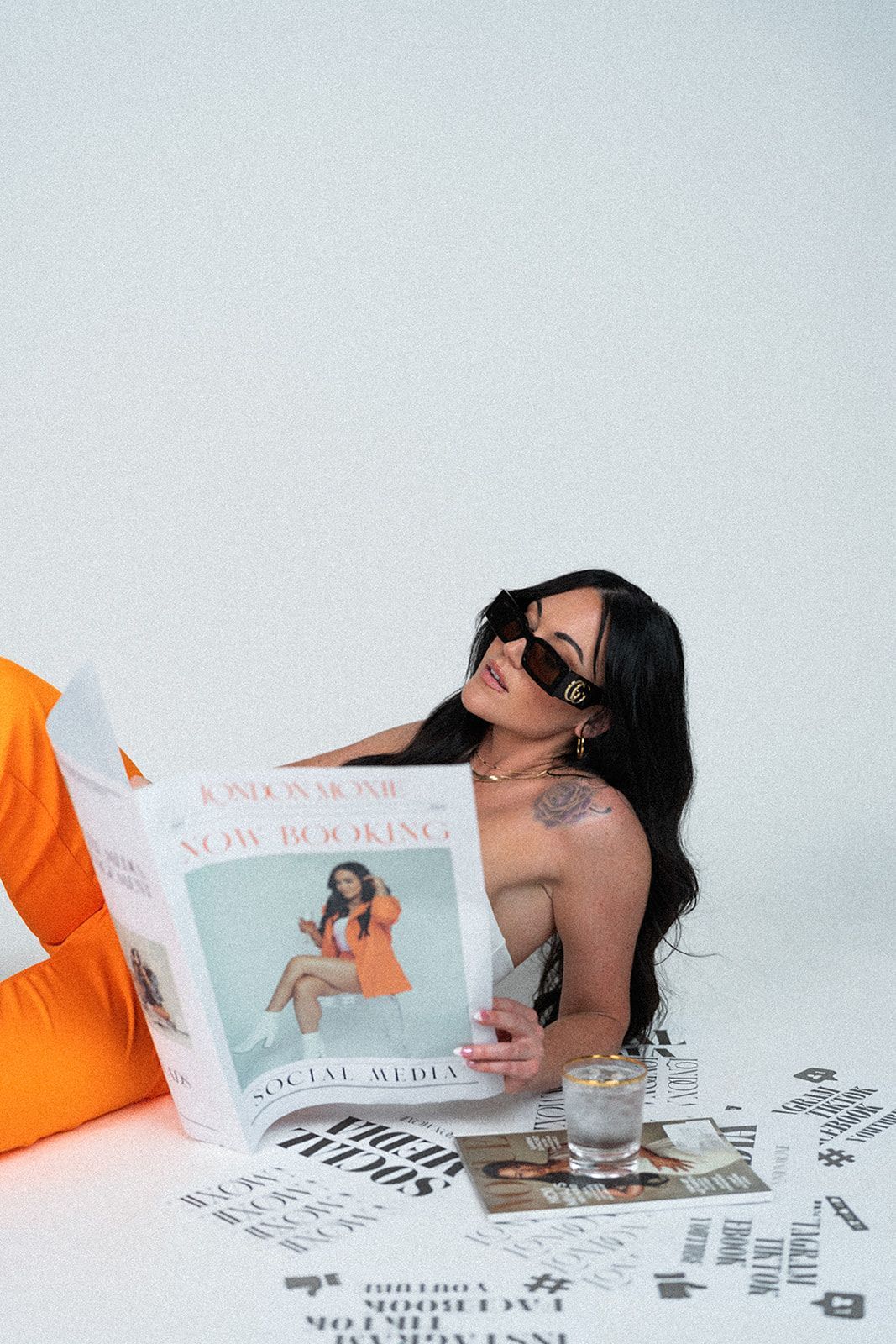 A woman is laying on the floor reading a newspaper.