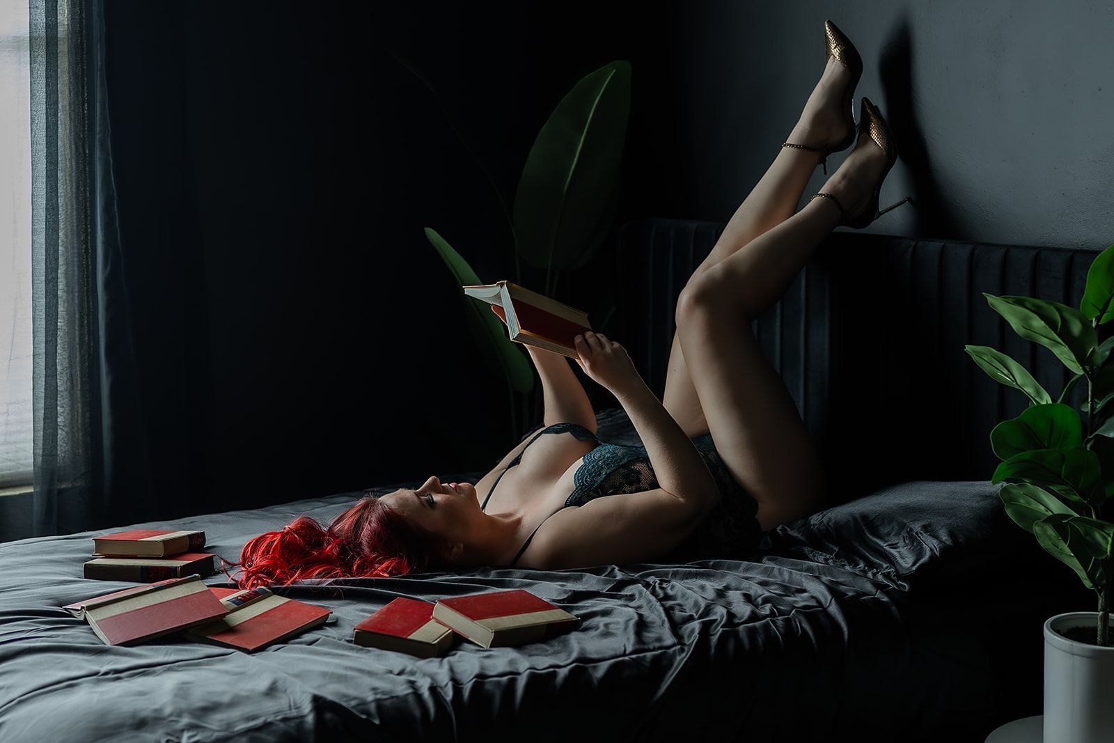 A woman in lingerie is laying on a black bed for a boudoir photo shoot in Medford, Oregon