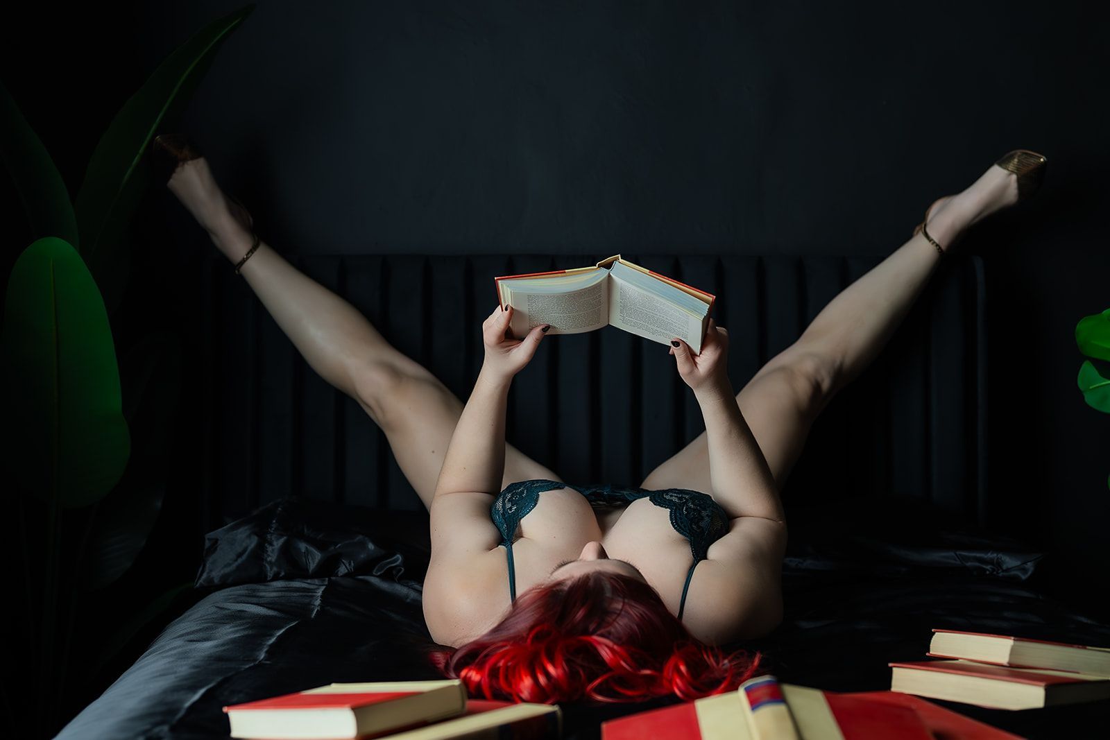 A woman in lingerie is laying on a black bed for a boudoir photo shoot in Medford, Oregon