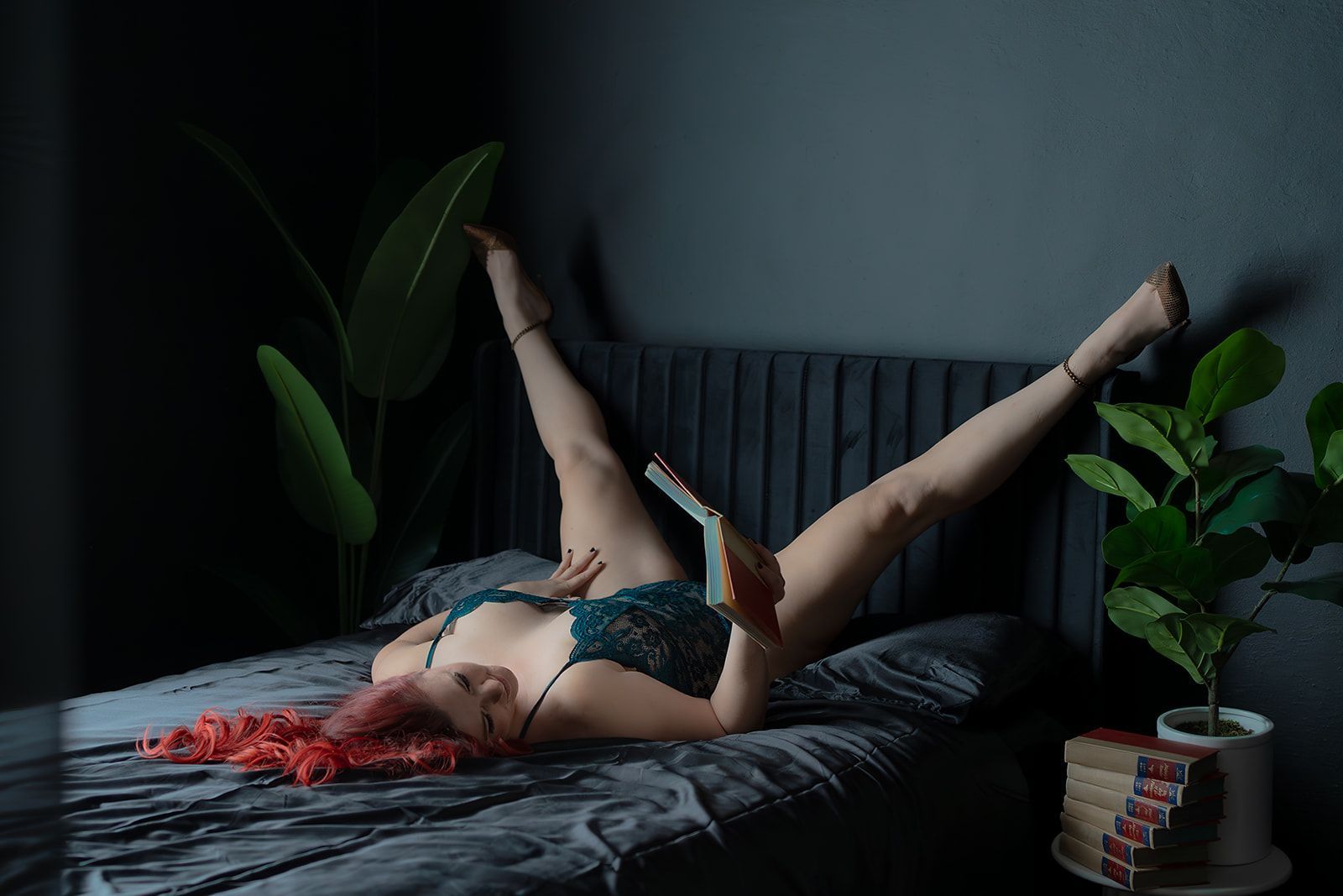 A woman in lingerie is laying on a black bed for a boudoir photo shoot in Medford, Oregon