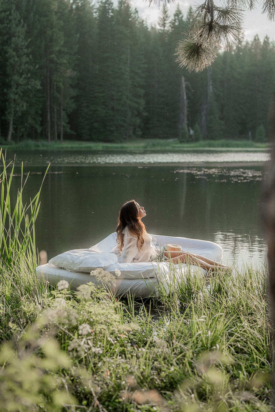 A woman is sitting in a boat in the middle of a lake.