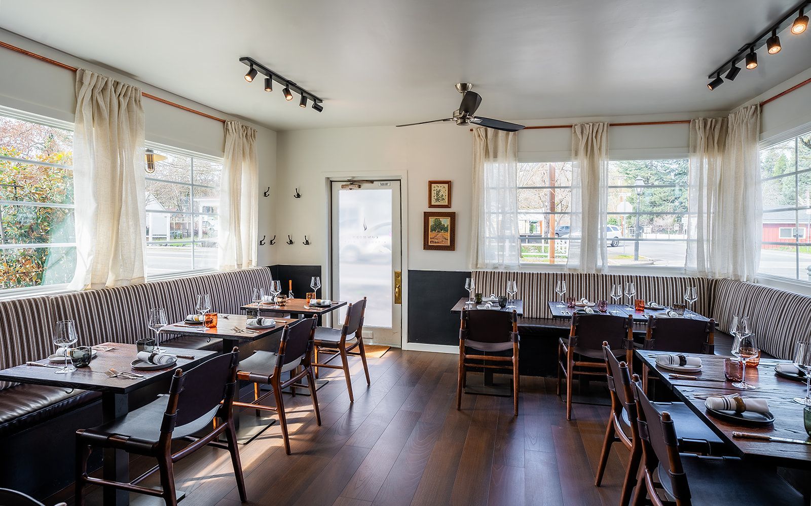 A restaurant with tables and chairs and a lot of windows.
