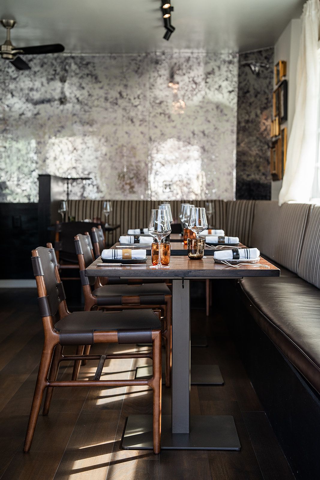 A dining room with tables and chairs set for a meal.