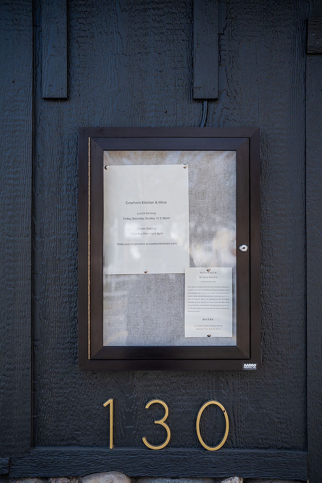A bulletin board on a black wall with the number 130 on it.