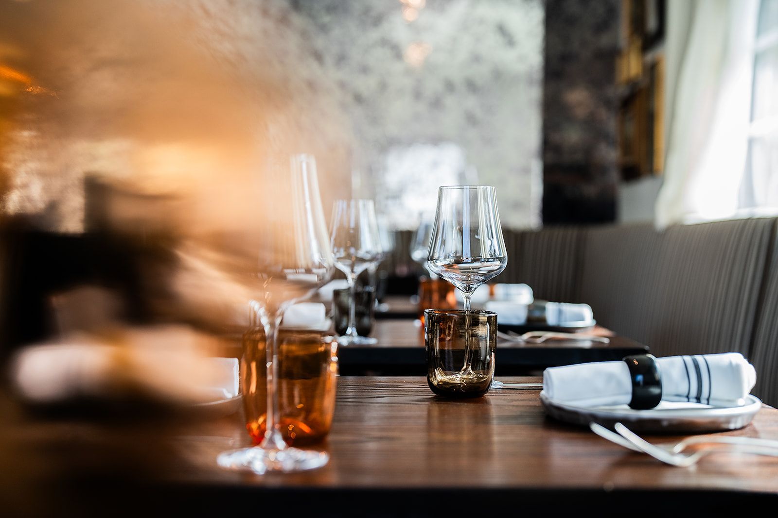 A table set for a dinner party in a restaurant with glasses of wine on it.