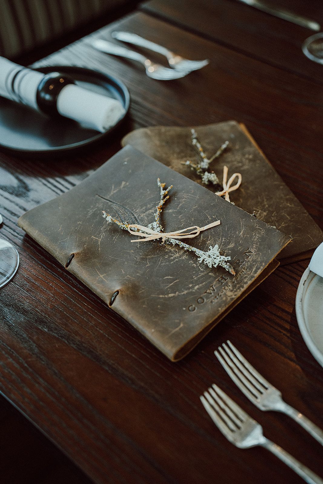 A book is sitting on a wooden table next to silverware.