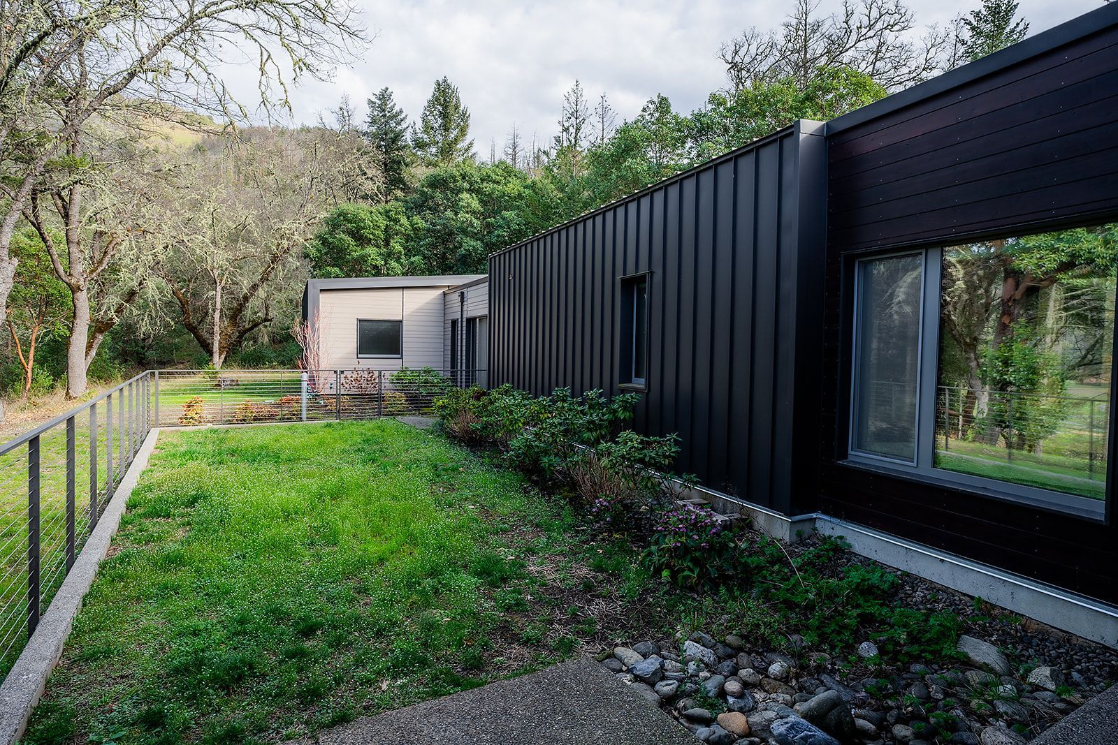 A house with a black fence and a large yard in front of it.