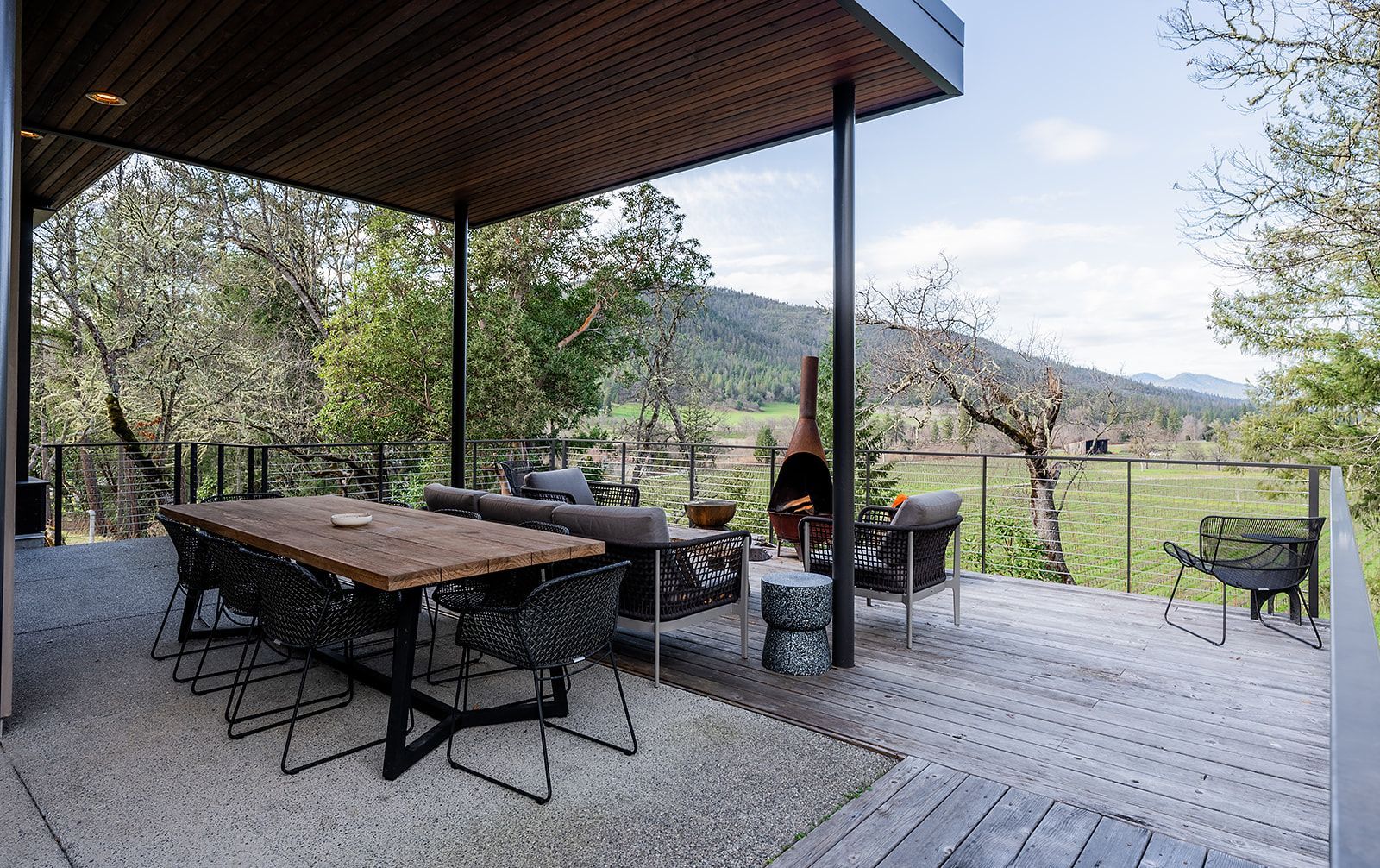 There is a table and chairs on the deck with a view of the mountains.