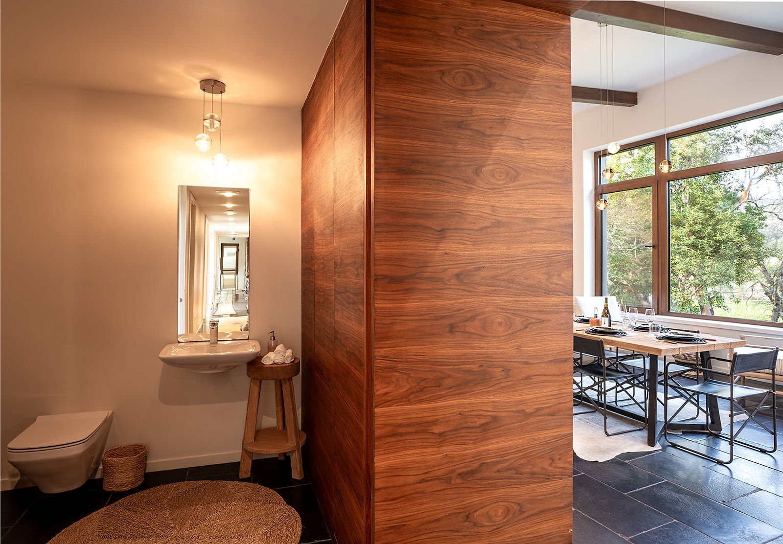 A bathroom with a wooden wall between it and a dining room.