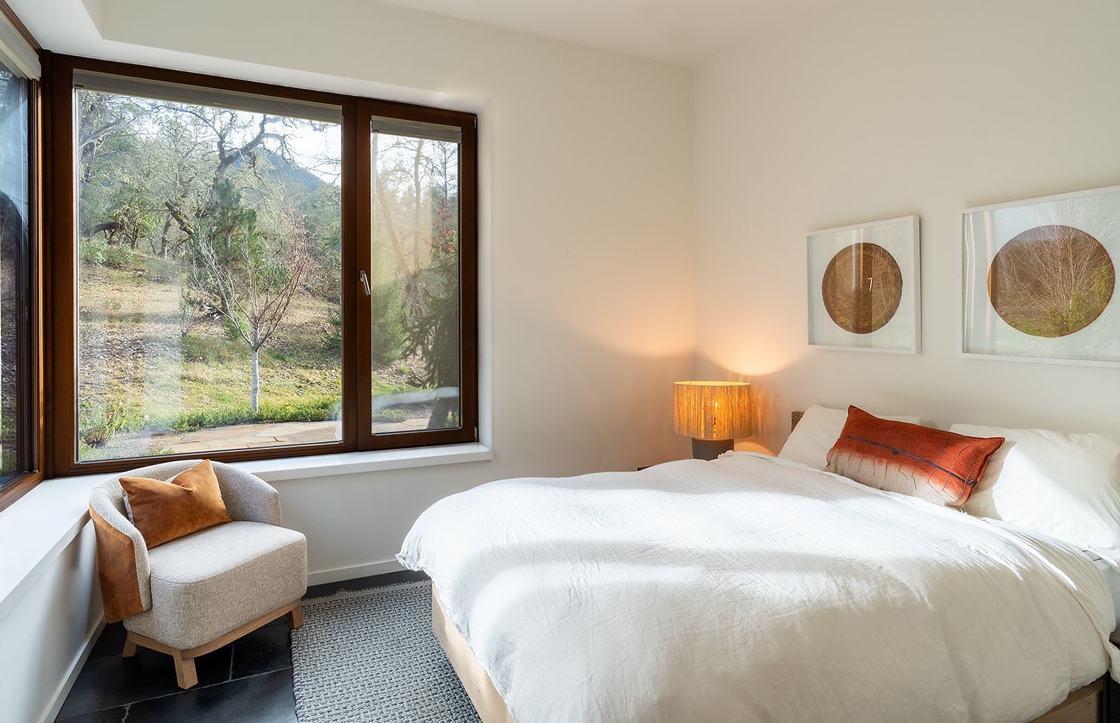 A bedroom with a bed , chair , lamp and window.
