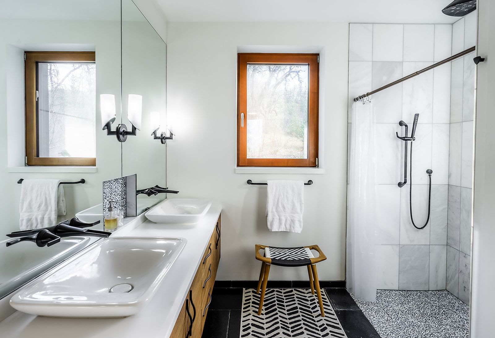 A bathroom with two sinks and a walk in shower.