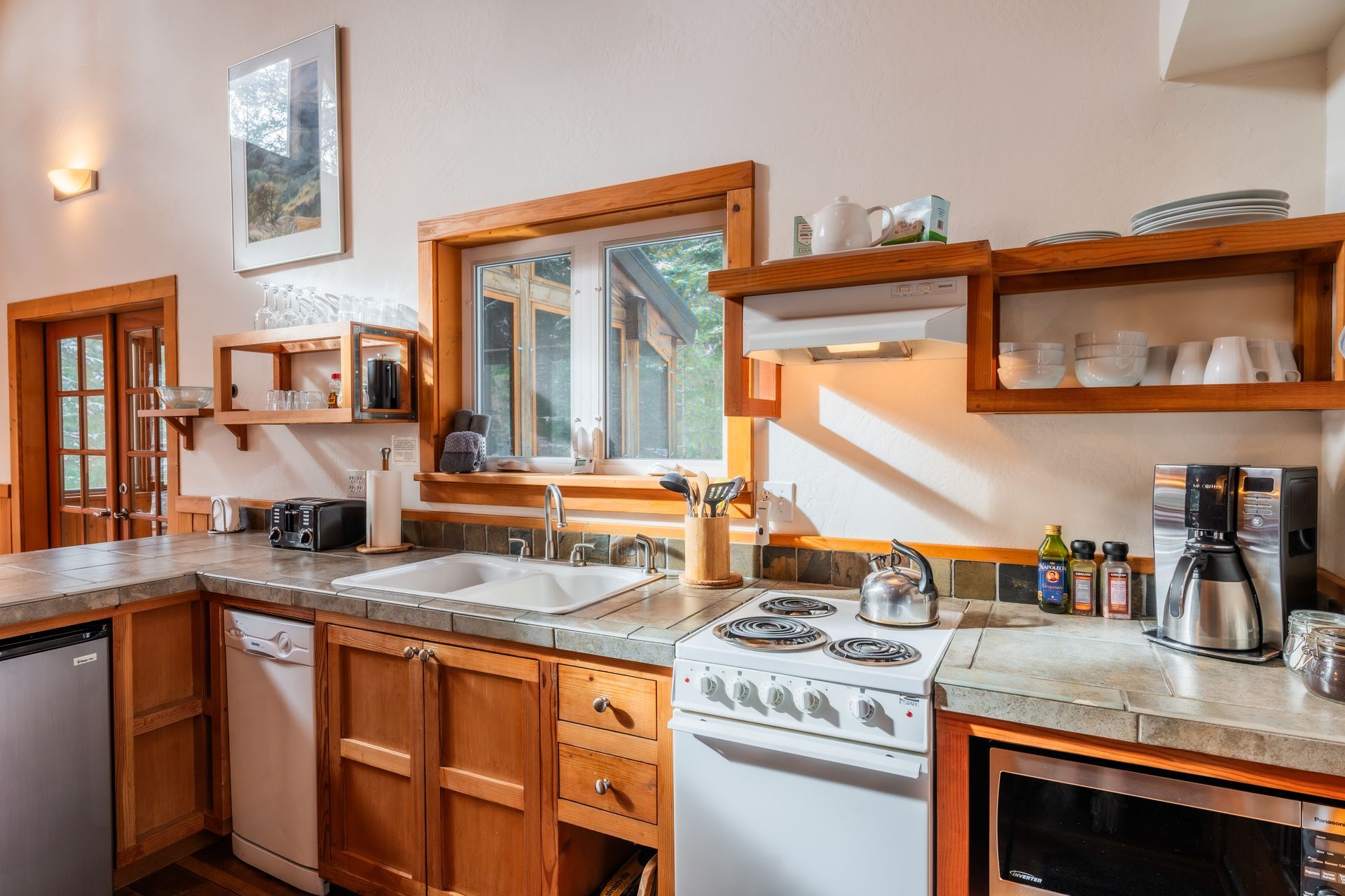 A kitchen with a stove , sink , dishwasher , and microwave.