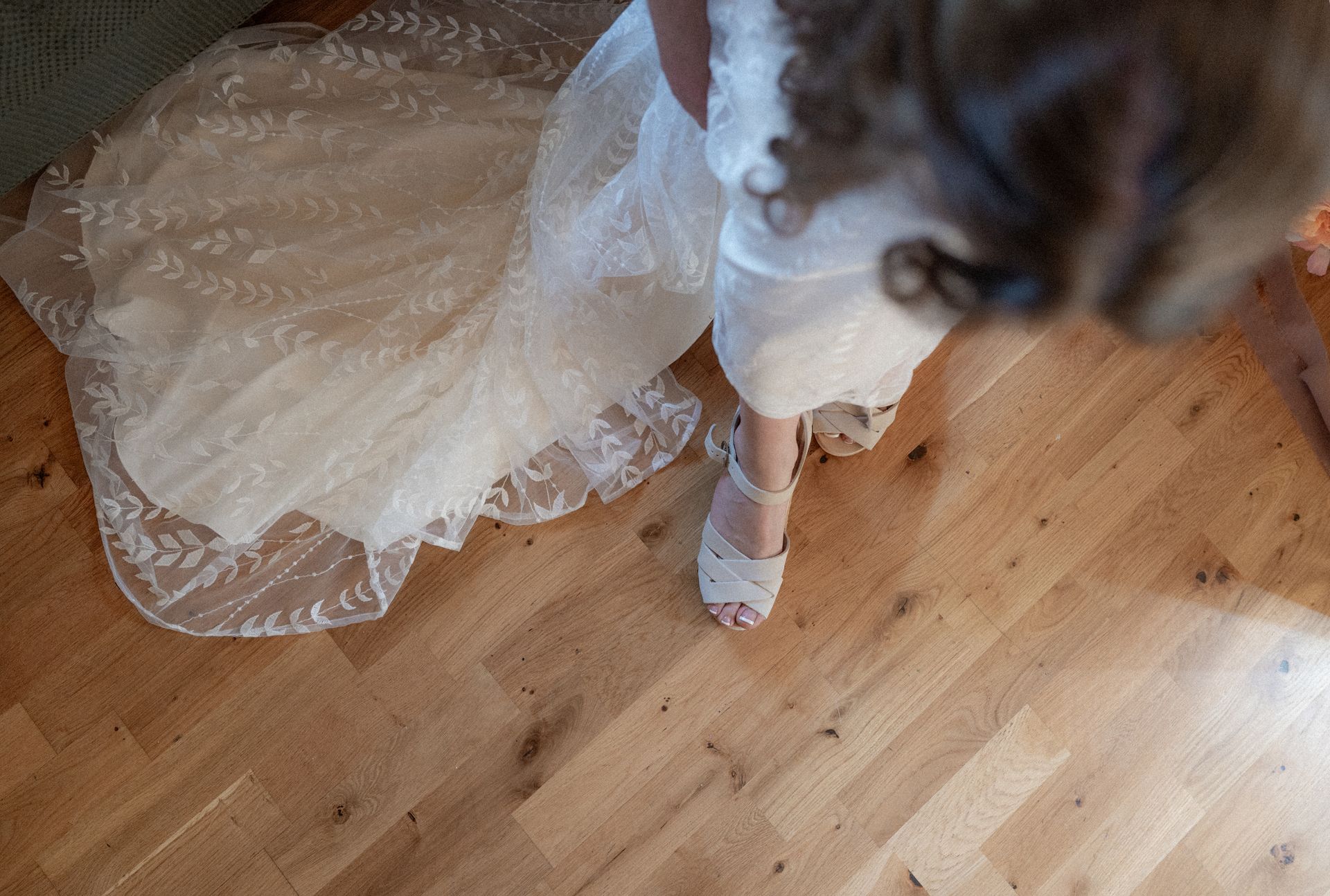 A woman in a wedding dress is standing on a wooden floor.