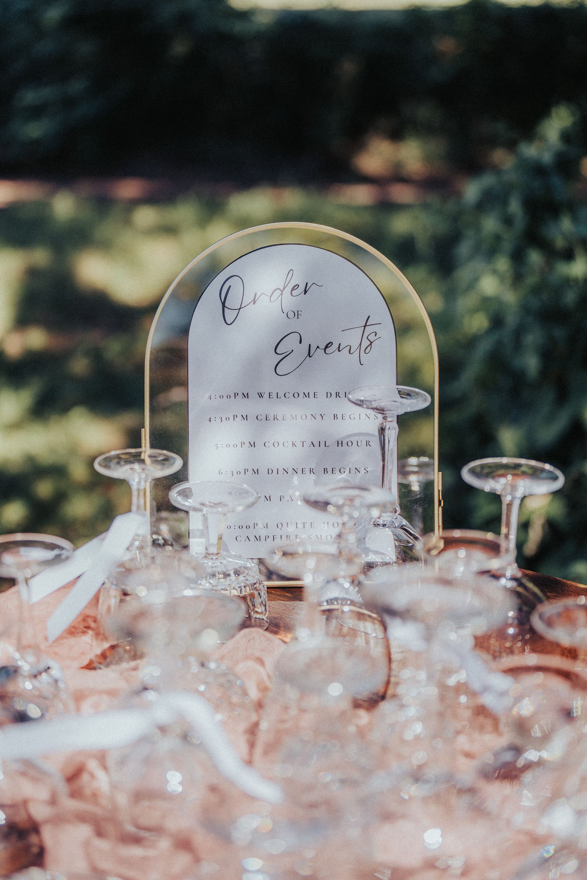 A bunch of champagne glasses are sitting on a table with a sign in the background.