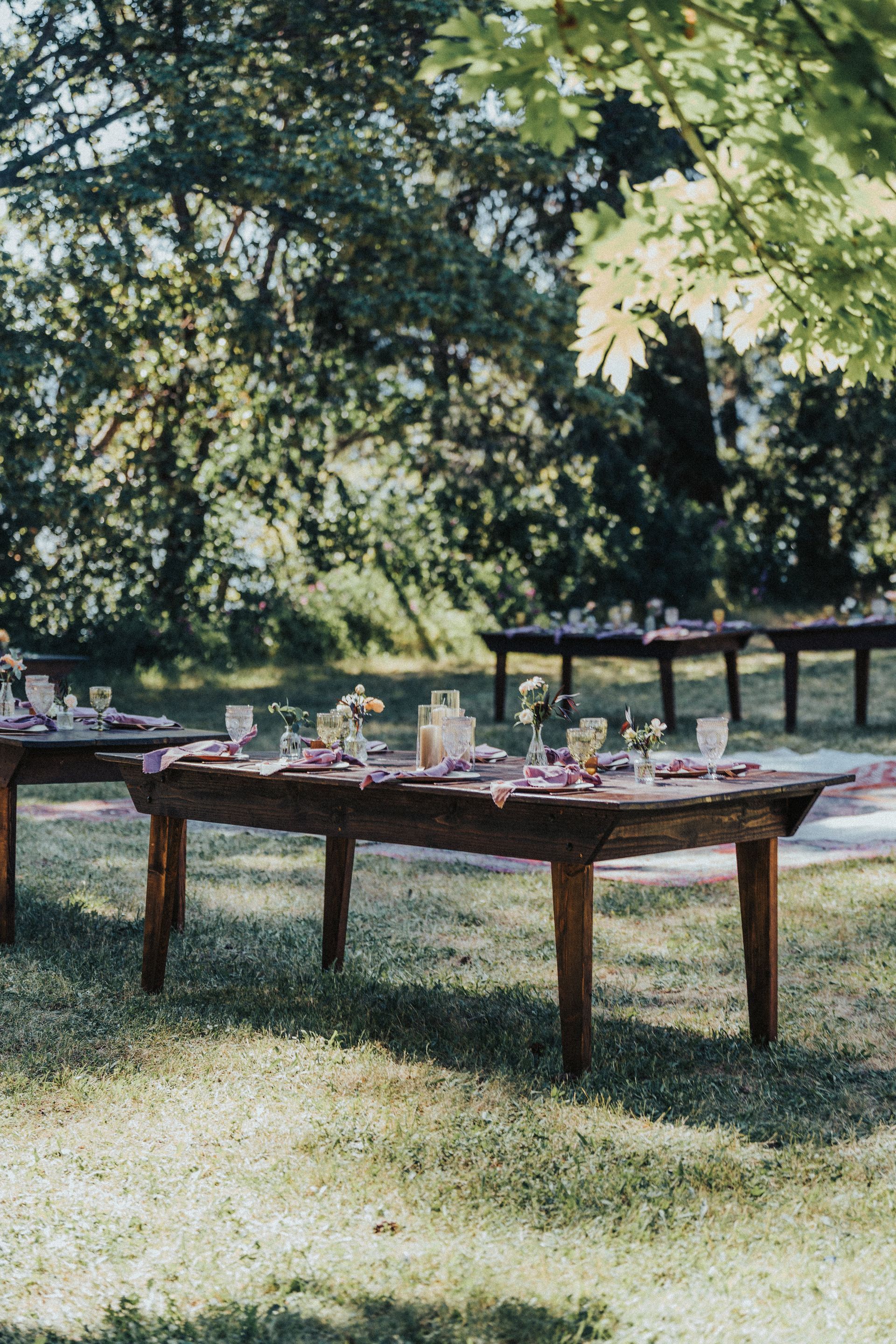 A row of wooden tables sitting on top of a lush green field.